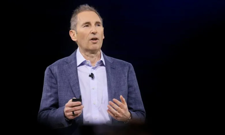 Andy Jassy speaks on stage, wearing a blue blazer and light blue shirt.