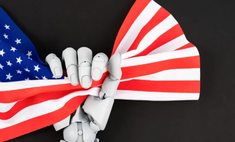 Robot hand holds American flag against a black background.