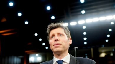 Man in suit and tie looking up at lights in dark room.