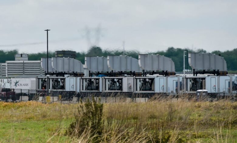 Rows of modular data center units with cooling systems, cloudy sky.
