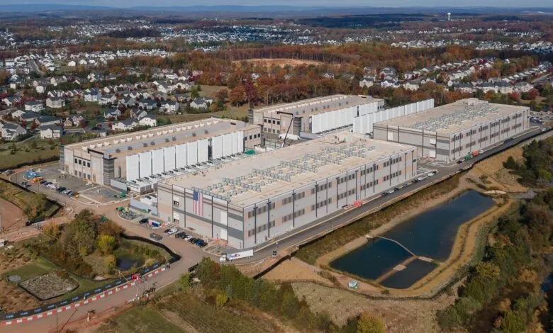 Aerial view of large data center complex near residential area and lake.