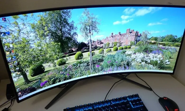 Ultrawide curved monitor displaying a landscape with a large building and garden.