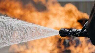 Water stream from nozzle aimed at flames, fire safety demonstration.