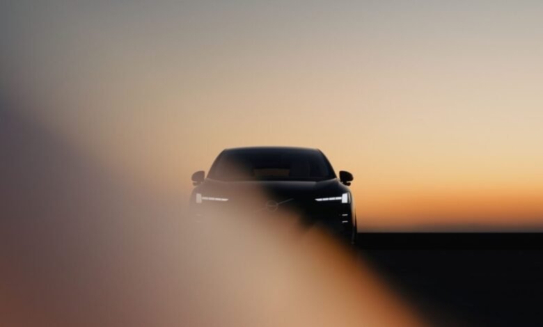 Sleek Volvo EX60 electric car front view against a gradient sunset background.