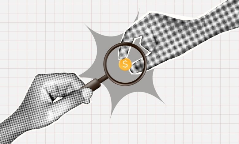 Two hands holding magnifying glass over dollar coin on graph paper.