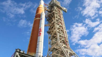 NASA's Artemis rocket on launchpad against blue sky with clouds.