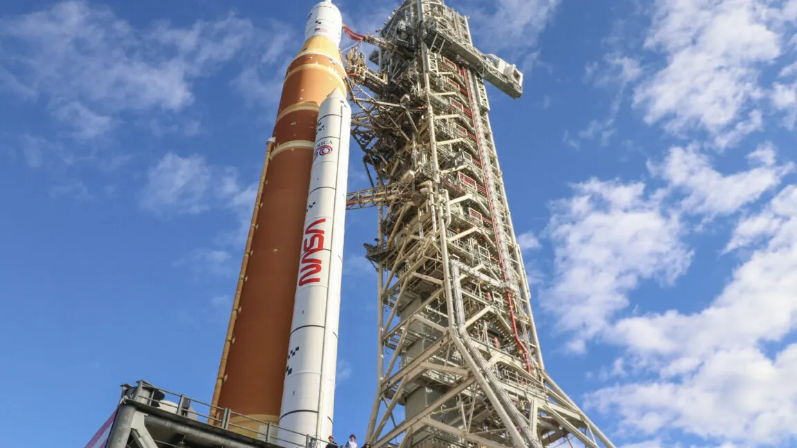 NASA's Artemis rocket on launchpad against blue sky with clouds.