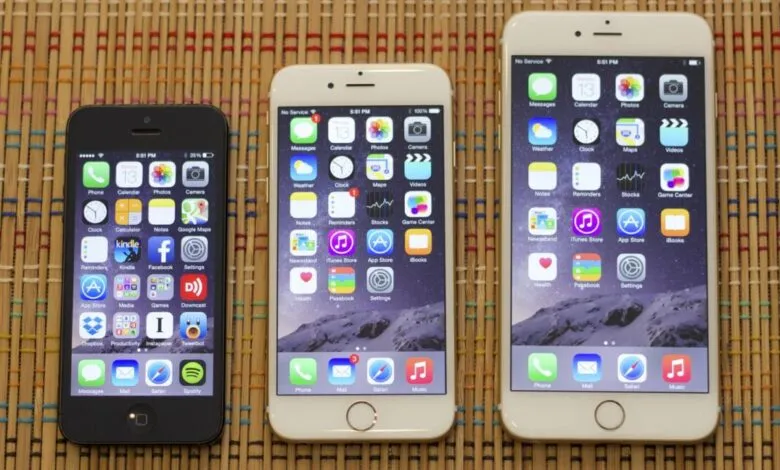 Three iPhones of different sizes are displayed on a textured surface.