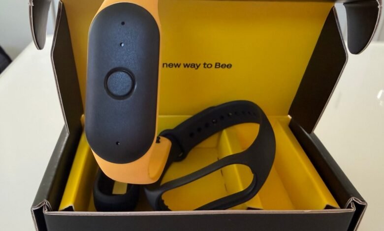 Bee wearable device in its box, featuring a black and orange design.