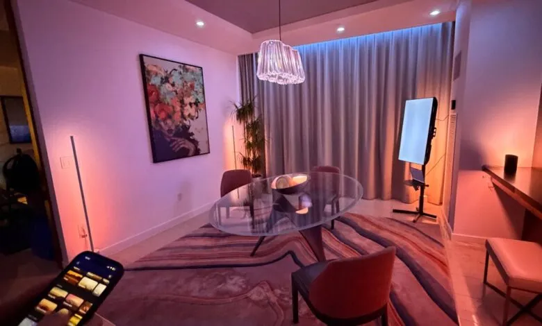 Dining room with glass table, modern art, and smart lighting controlled by a phone.