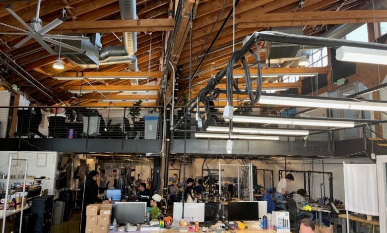 Busy open office space with exposed wooden beams and multiple workstations.