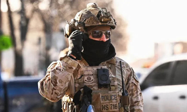 Police officer in tactical gear with sunglasses and helmet.