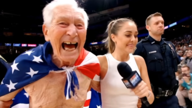Elderly man with American flag draped over shoulders, interviewed at event.