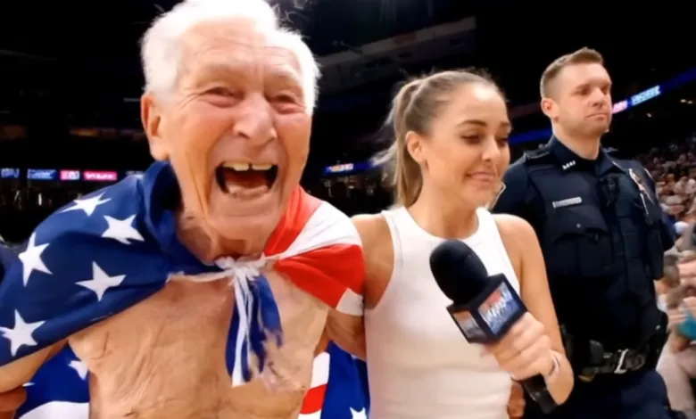 Elderly man with American flag draped over shoulders, interviewed at event.