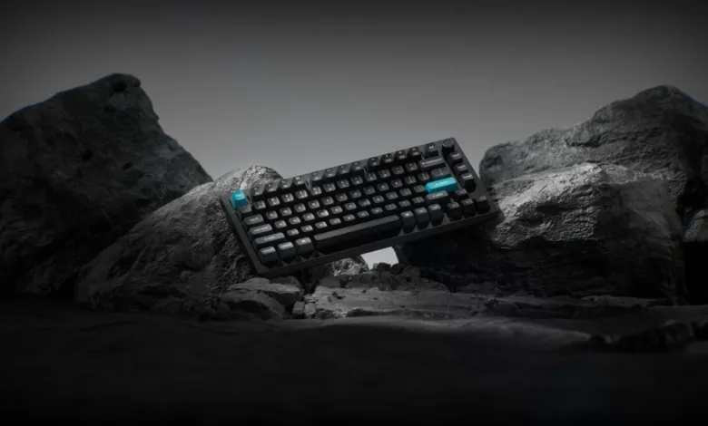 Black Keychron Q1 Ultra keyboard with blue accents on rocky terrain.