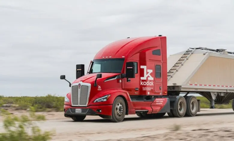 Red Kodiak Robotics semi-truck driving on a dirt road with trailer attached.