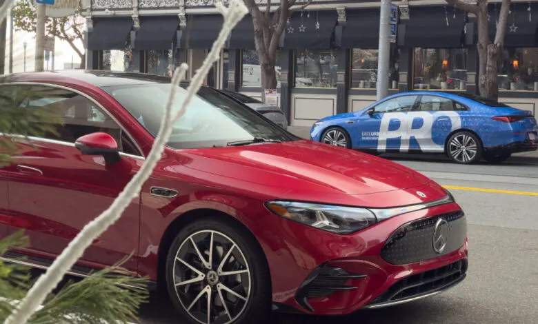 Red Mercedes-Benz parked on a city street with a blue Mercedes in the background.