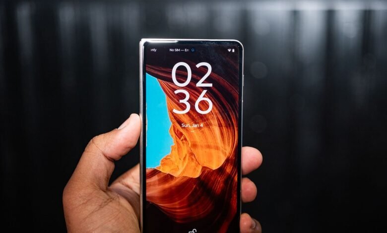 Hand holding a Motorola Razr foldable phone displaying the time 02:36.