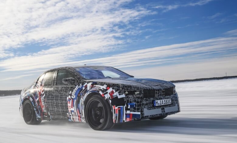 Camouflaged BMW prototype driving on snow-covered surface.
