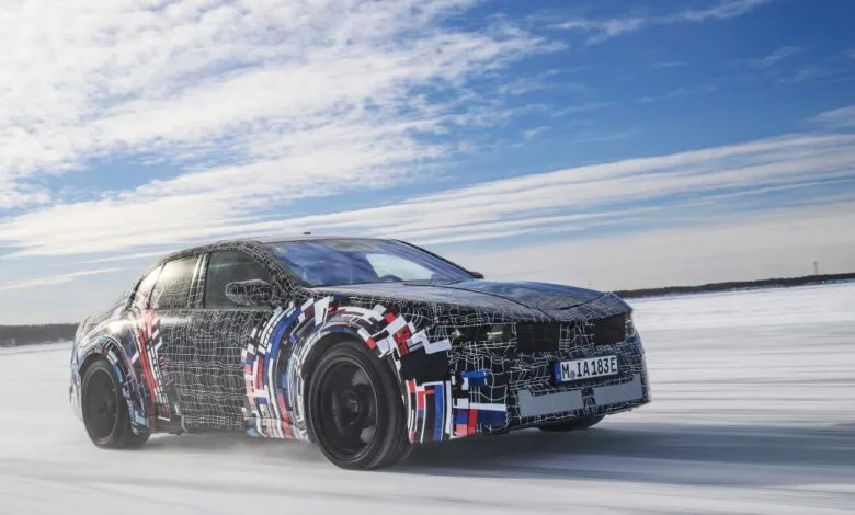Camouflaged BMW prototype driving on snow-covered surface.