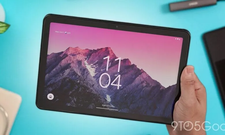 Hand holding a Pixel Tablet displaying the time 11:04 and a mountain background.