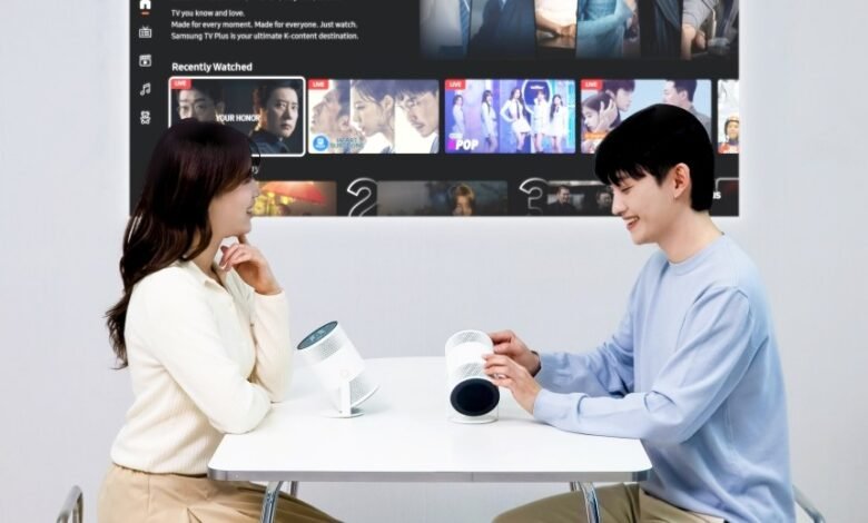 Couple watches Samsung Freestyle projector displaying streaming content.