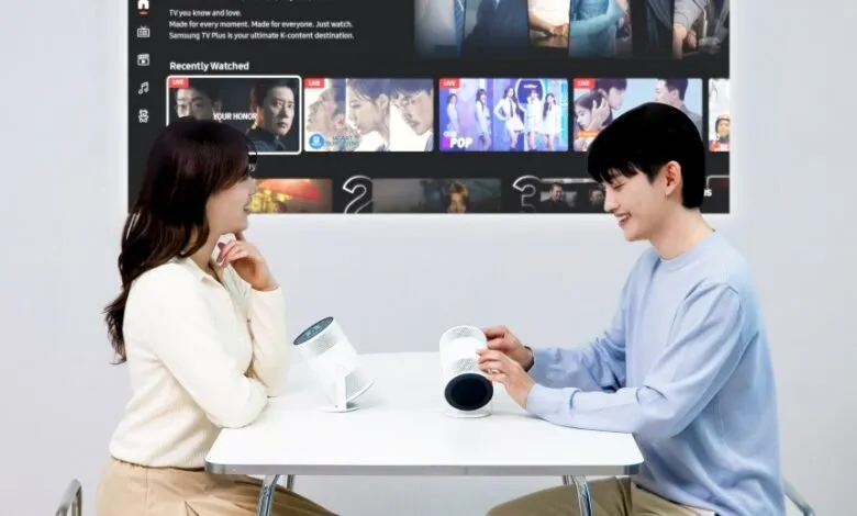 Couple watches Samsung Freestyle projector displaying streaming content.