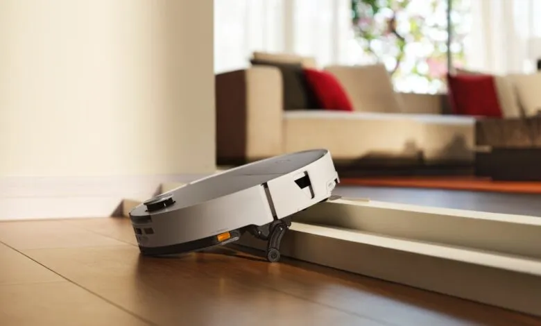 Robot vacuum cleaner navigating over a door threshold in a modern living room.