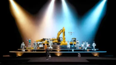 Robots and construction vehicles on a lit stage, person in foreground.