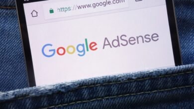 Smartphone displaying Google AdSense website in jeans pocket.