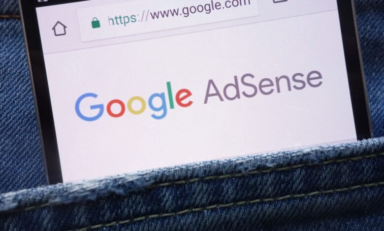 Smartphone displaying Google AdSense website in jeans pocket.
