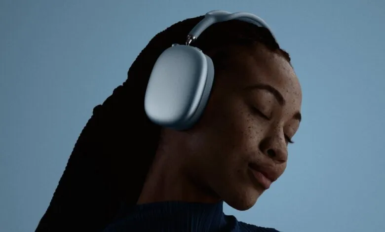 Woman with closed eyes wearing blue Apple AirPods Max headphones.