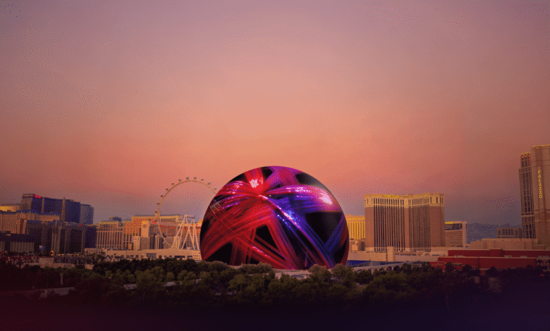 Las Vegas Sphere illuminated with red and purple lights against city skyline.