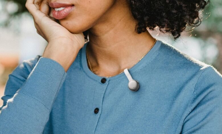 Person wearing a small, white wearable device clipped to their blue cardigan.