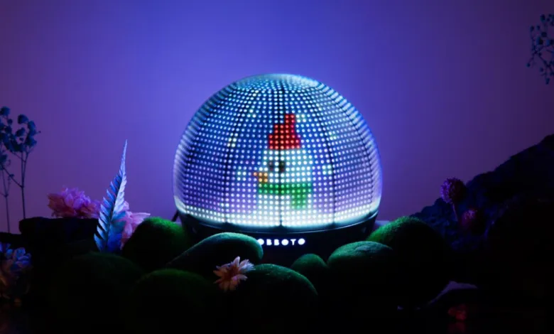 OBBOTO displays a pixelated gnome on a dome-shaped screen, surrounded by moss and flora.