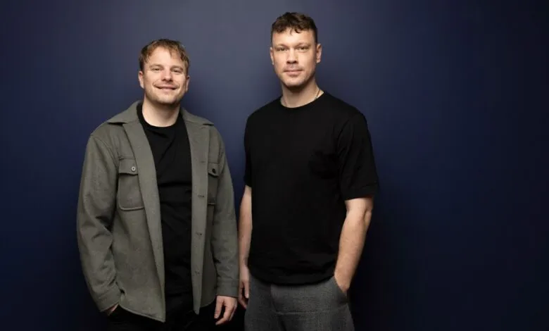 Steffen Tjerrild and Victor Riparbelli pose against a dark blue wall.