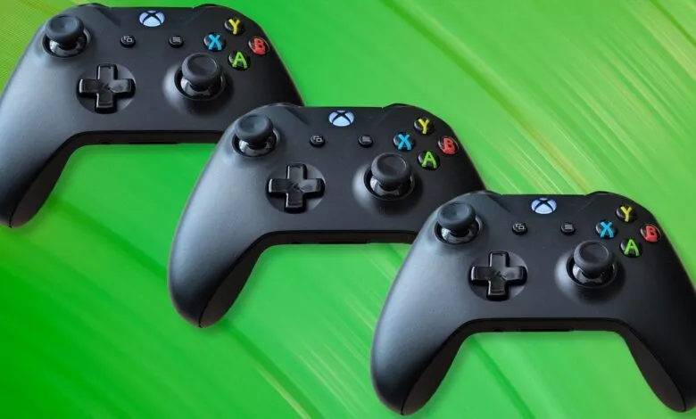 Three black Xbox controllers arranged on a green background.