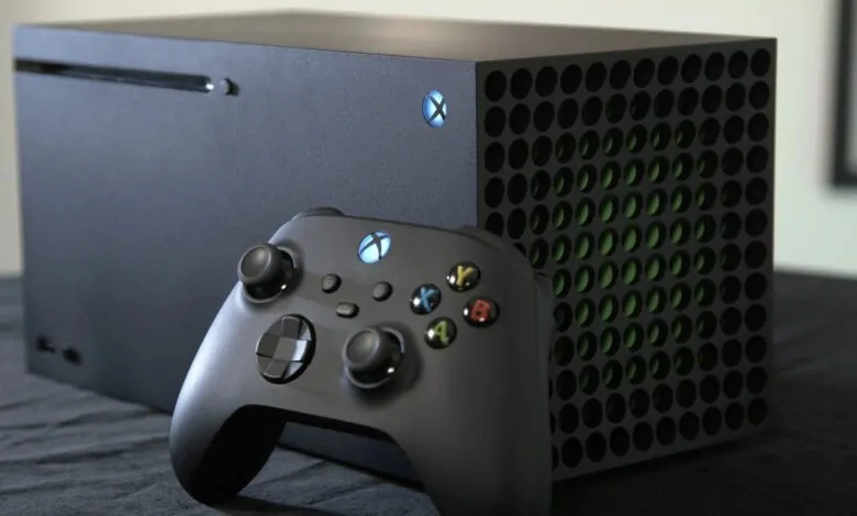 Xbox Series X console and controller on a dark surface.