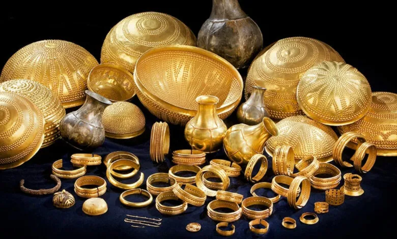 Treasure of Villena: Gold bowls, bracelets, and vessels on dark surface.