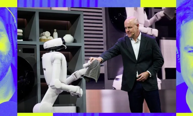 Man in suit interacts with white robot in laundry setting on stage.