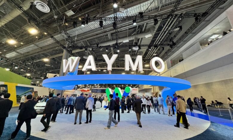 Waymo exhibit at CES with large logo and crowd of people.