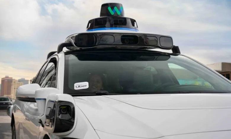 White Waymo self-driving car with Uber sticker and passenger.
