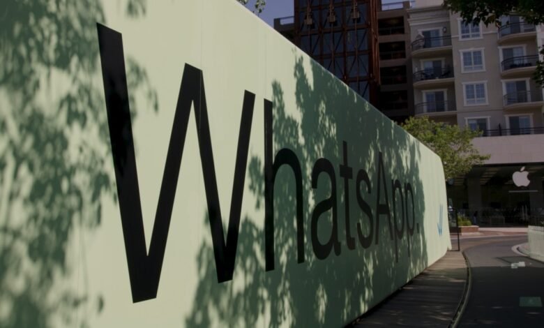 Large WhatsApp sign outside building with tree shadows.