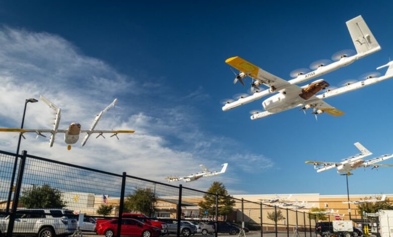 Multiple Wing delivery drones in flight near a Walmart store, clear blue sky.