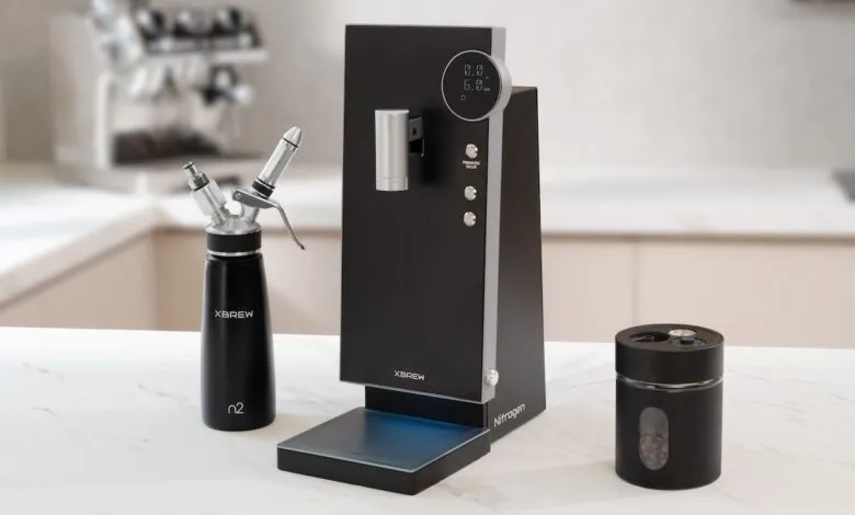 Xbrew Nitro coffee maker with dispenser and bean container on marble countertop.