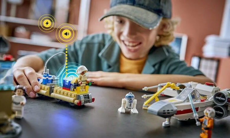 Boy smiles while playing with Star Wars LEGO set featuring sound and light effects.
