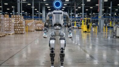 Boston Dynamics robot stands in a warehouse, facing forward.