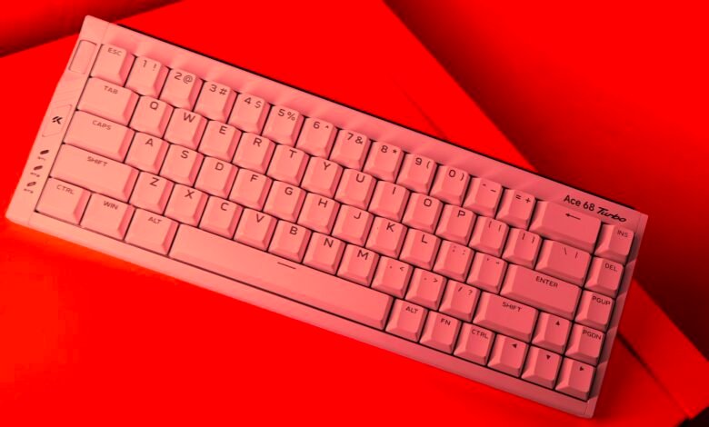 Compact white Ace 68 Turbo keyboard with pink keycaps on a red background.