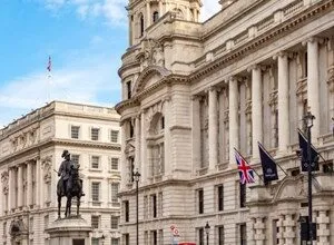 Whitehall, London street view with government buildings and a statue.