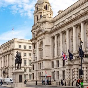 Whitehall, London street view with government buildings and a statue.